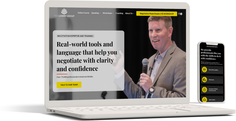 A white laptop and smartphone display a website for The Lowry Group, created by a web design company, showing a man speaking into a microphone about negotiation tools; yellow buttons prompt users to contact the team.